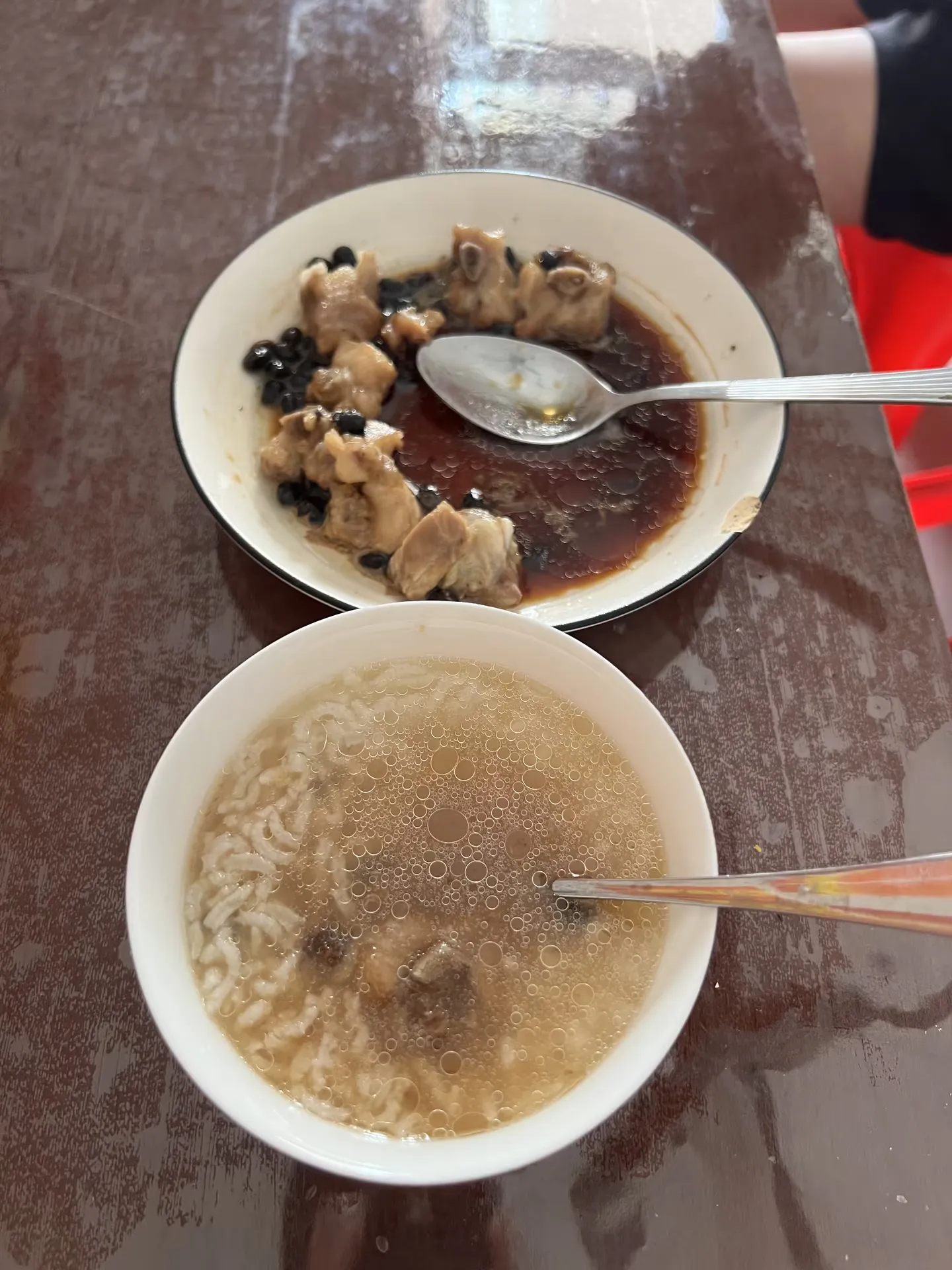 A meat dish and a bowl of rice porridge on the table